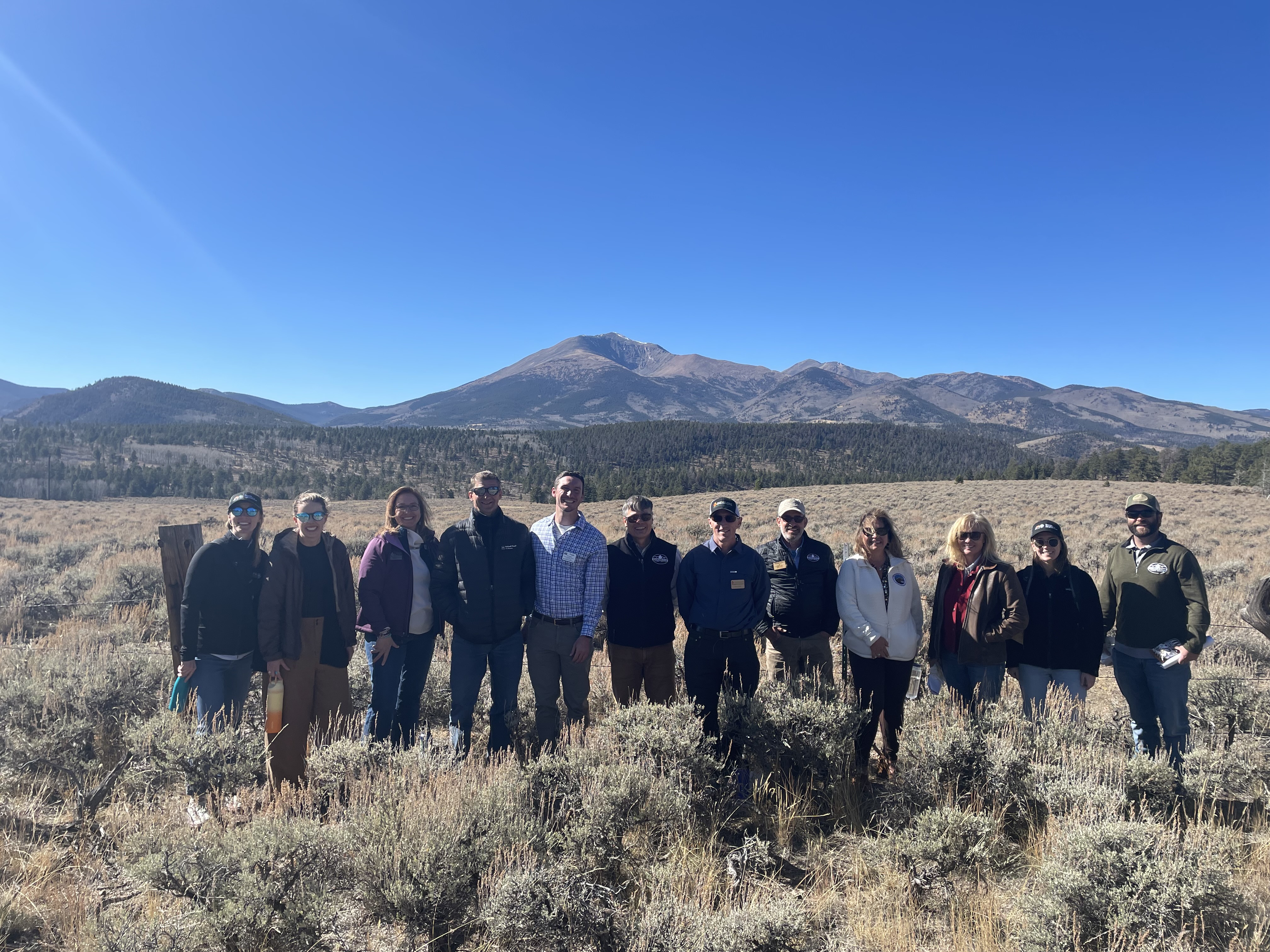 Council members stand in a line in front of a mountain range