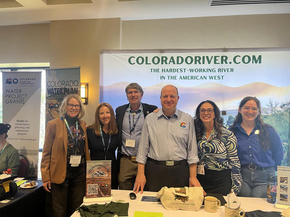 various state officials standing in front of the ColoradoRiver.com booth at Colorado Water Congress