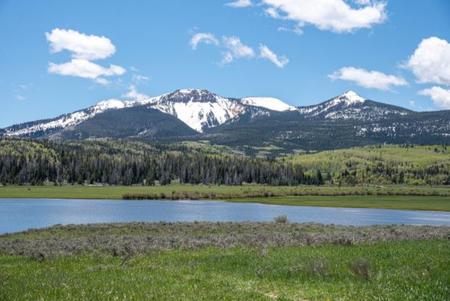 View of landscape with small lake in foreground and snow-capped mountains in the background