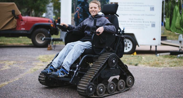 Young boy in a track-chair - an all terrain wheelchair that uses triangular tracks instead of wheels
