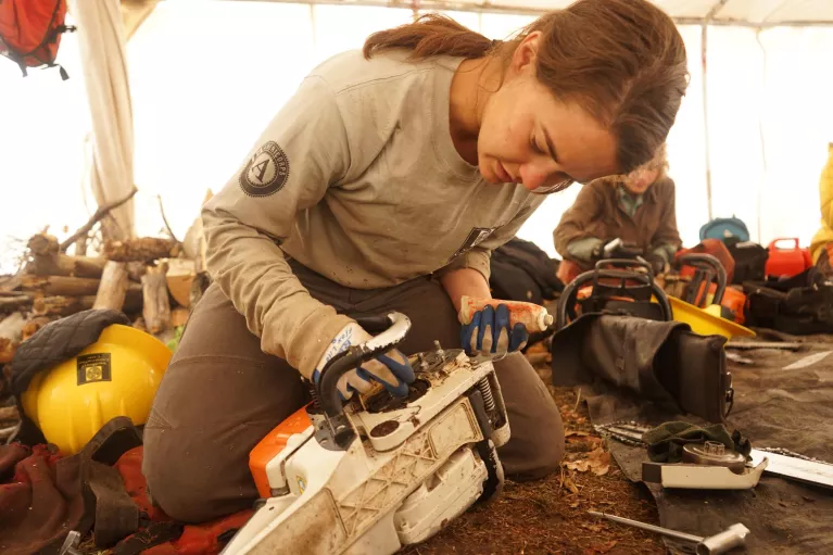 CYCA crew member cleans her chainsaw